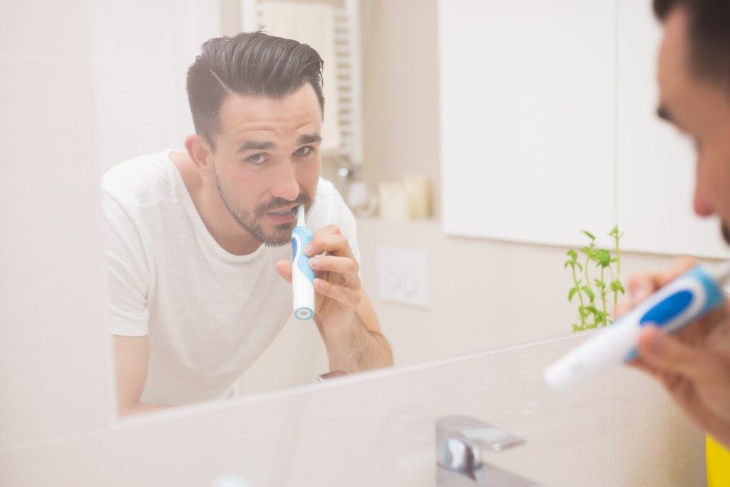 Man looking in the mirror while brushing his teeth