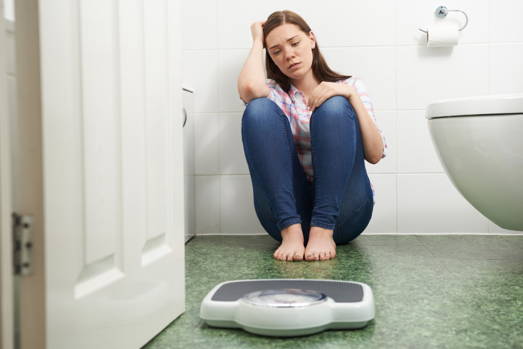 woman sad and looking at a weighing scale