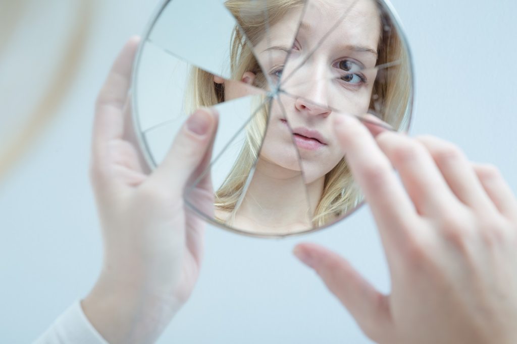 woman holding a broken mirror